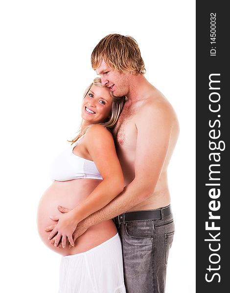 Shirtless young couple stand affectionately with the husband holding his pregnant wife in his arms. Isolated on white. Shirtless young couple stand affectionately with the husband holding his pregnant wife in his arms. Isolated on white.