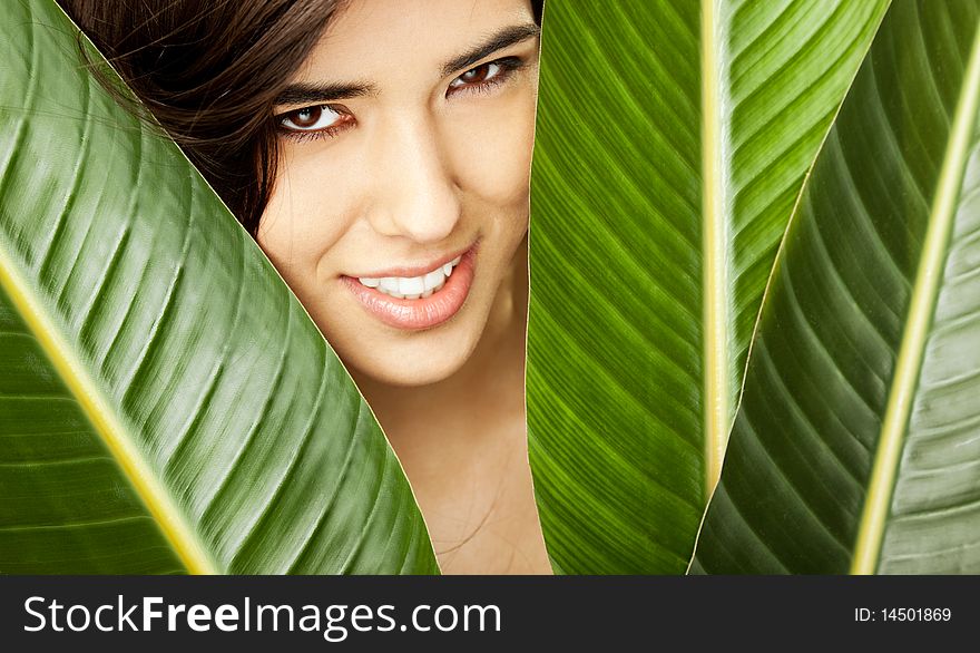 Beautiful young female posing with face between exotic flower leaves. Beautiful young female posing with face between exotic flower leaves