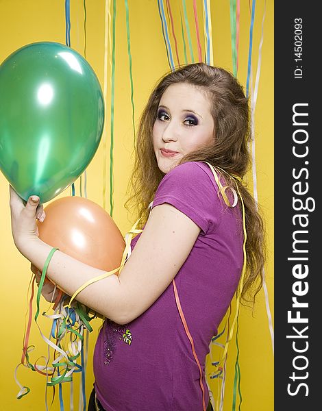 Young pretty girl with balloons and paper streamer in studio