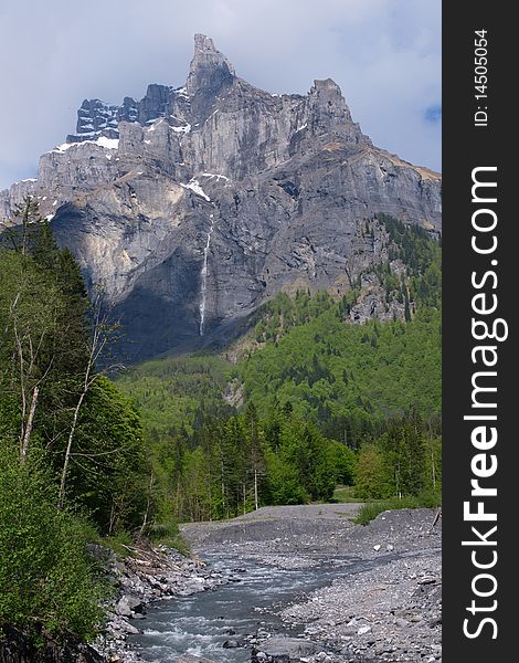 Vertical mountain landscape with small river in Alps, France.