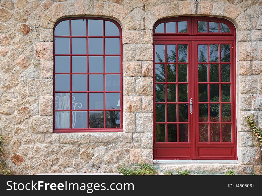 Red glassed door and windows with shutter in britany france