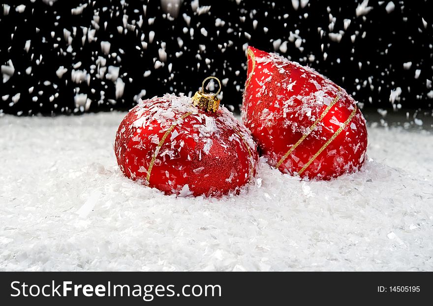 Image of snow falling on two red ornaments