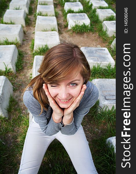 The young cheerful girl sits on a stone. The young cheerful girl sits on a stone