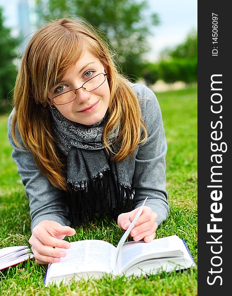 The girl lays on a green grass, and reads the book. The girl lays on a green grass, and reads the book