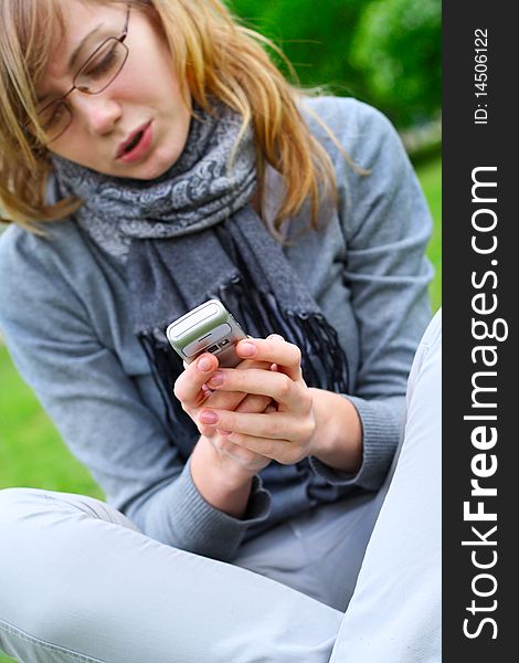 The girl sits, and holds a mobile phone in hands. The girl sits, and holds a mobile phone in hands