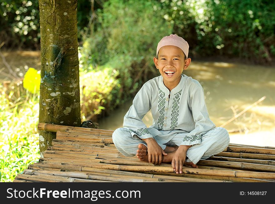 Happy Muslim boy sitting by the pond. Happy Muslim boy sitting by the pond