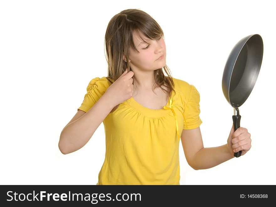 Girl looks in reflexion at bottom of frying pan isolated in white