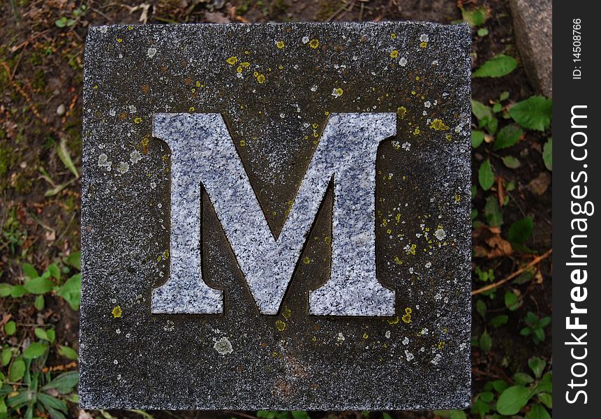Block with letter M stone, in ground. Block with letter M stone, in ground