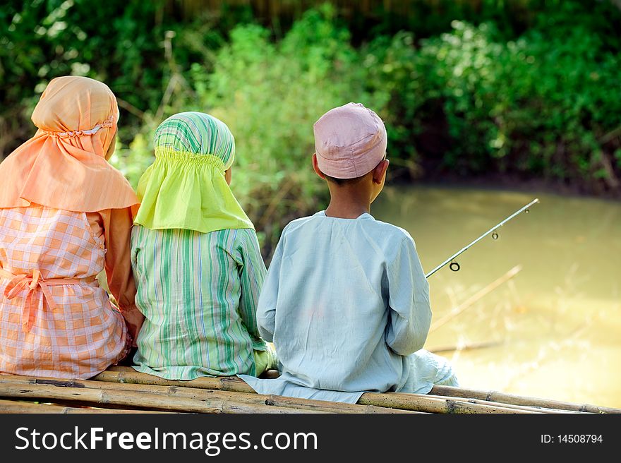 Muslim  kids fishing in a pond. Muslim  kids fishing in a pond
