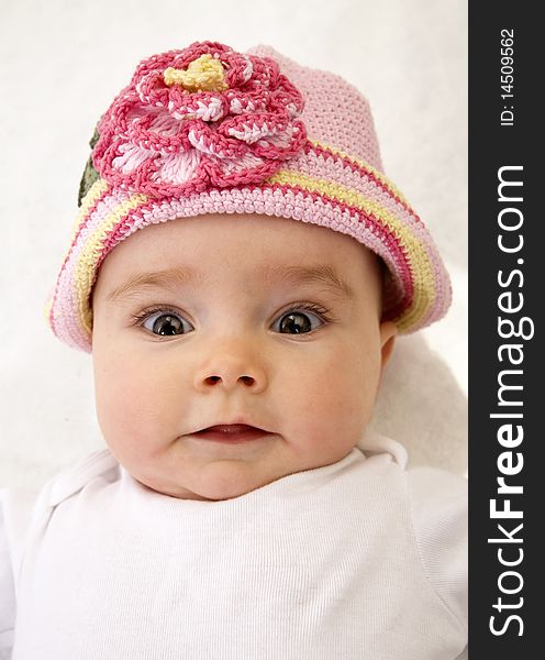 A close up of an infant wearing a pink hat  with a surprised look on her face. A close up of an infant wearing a pink hat  with a surprised look on her face.