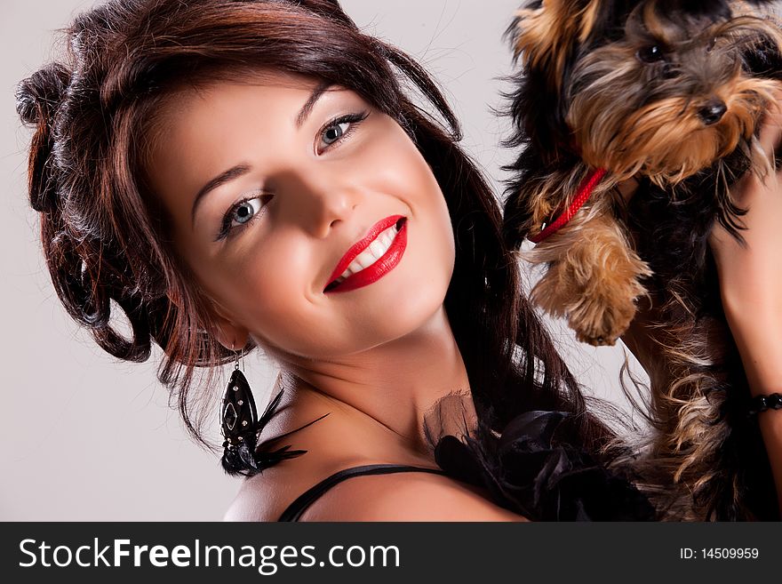 Young beautiful brunette woman in a black dress with a Yorkshire terrier. Young beautiful brunette woman in a black dress with a Yorkshire terrier