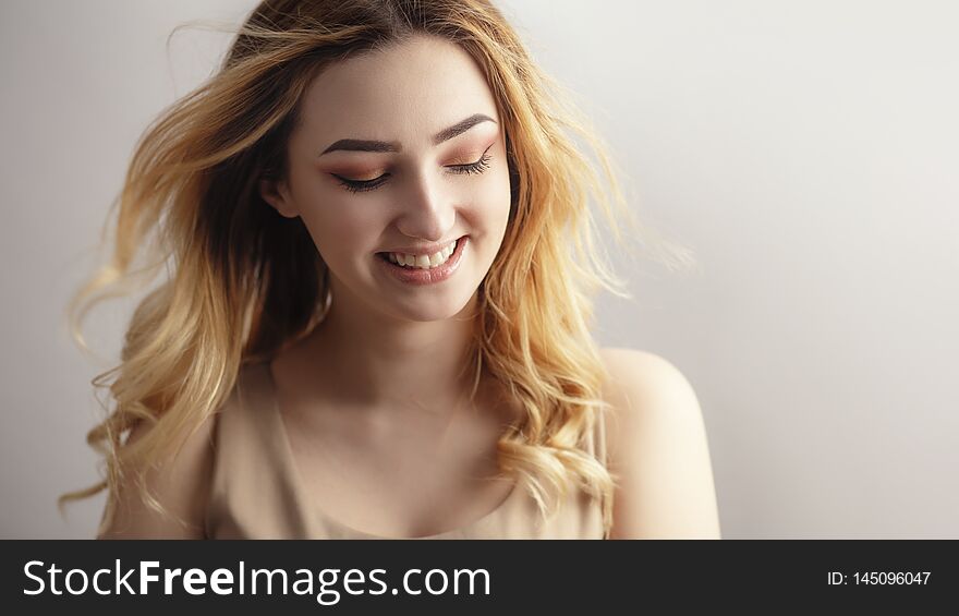 Studio portrait of a beautiful sincerely laughing girl, young woman face with curly hair disheveled from wind , the concept of