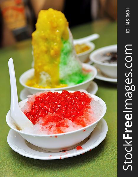 Bowl of ice kacang (red bean) dessert with mango and corn topping, and red ruby dessert. Bowl of ice kacang (red bean) dessert with mango and corn topping, and red ruby dessert