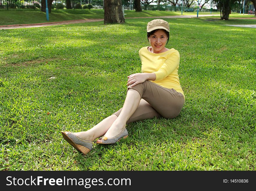 Young woman enjoying sunshine on green grass in park . Young woman enjoying sunshine on green grass in park