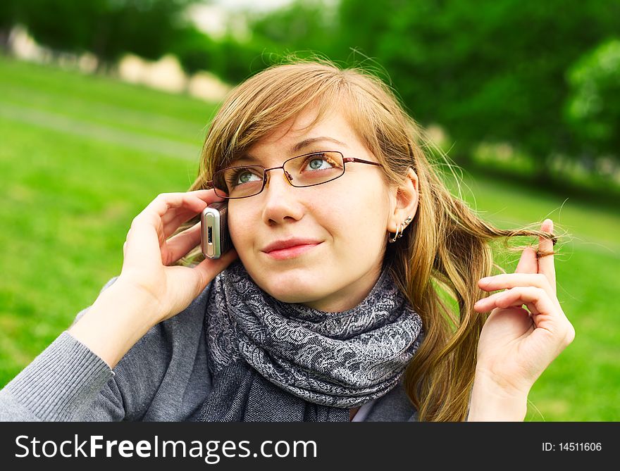 The young girl speaks by phone, in park. The young girl speaks by phone, in park