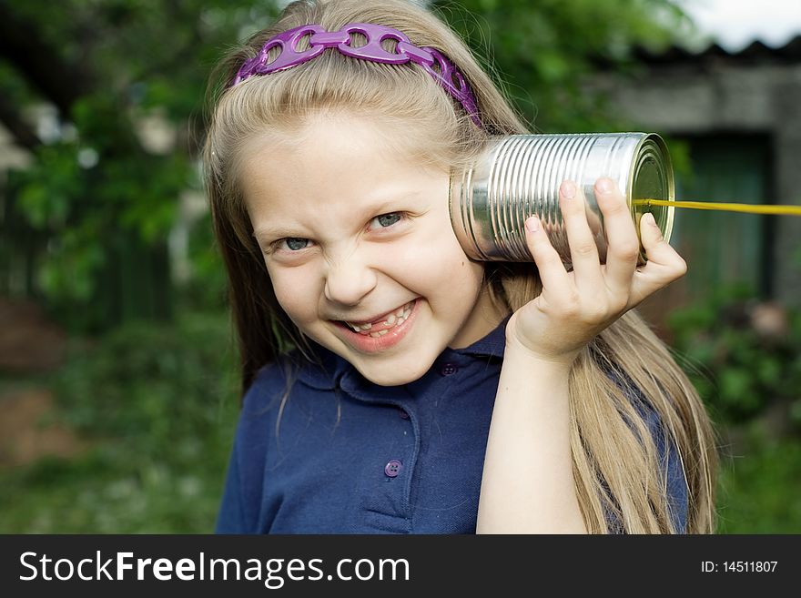 A girl playing with a toy-telephone outdoors