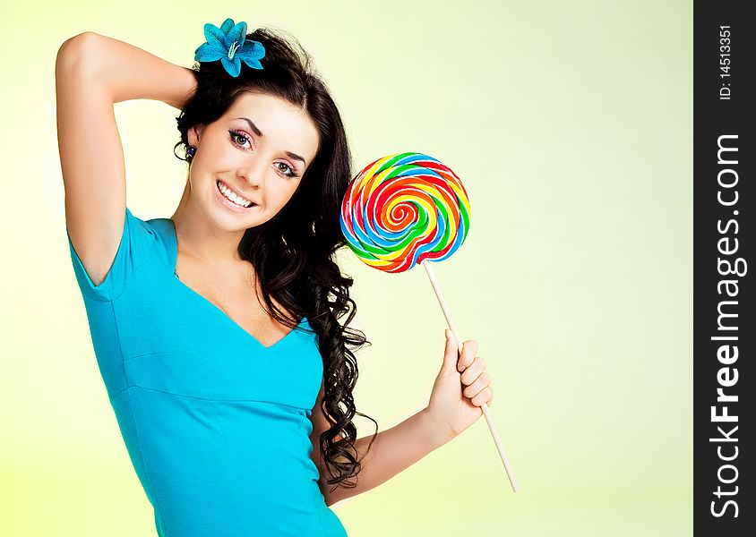 Pretty smiling brunette girl with a lollipop in her hand