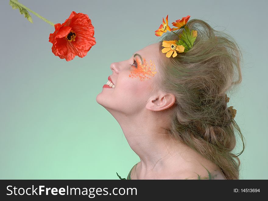 Portrait of forest nymph sniffing poppy