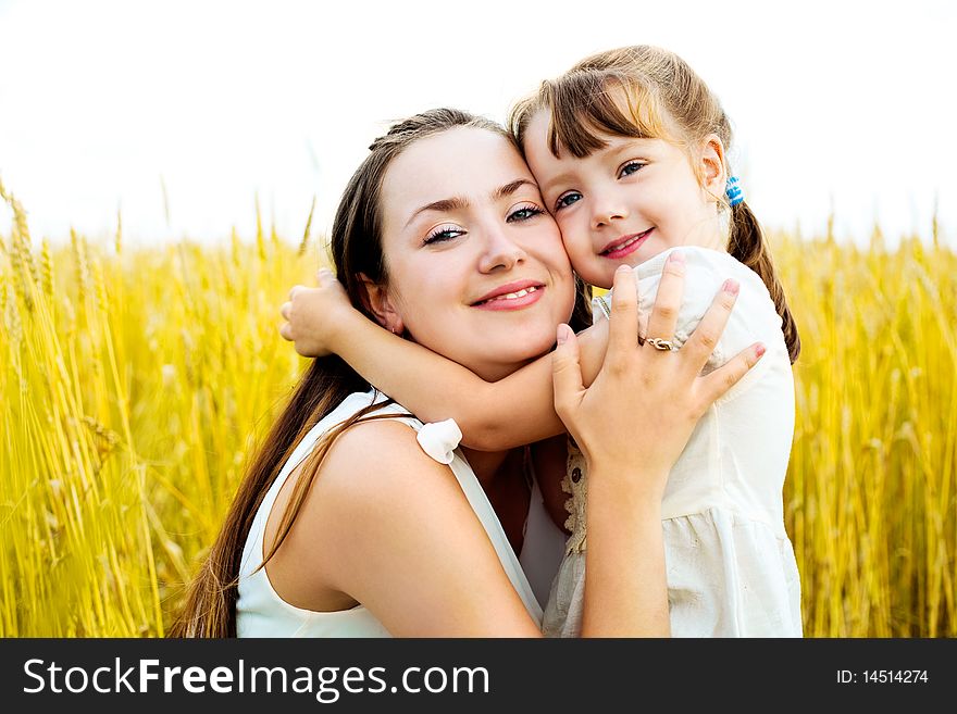 Young mother and her daughter at the wheat field on a sunny day. Young mother and her daughter at the wheat field on a sunny day