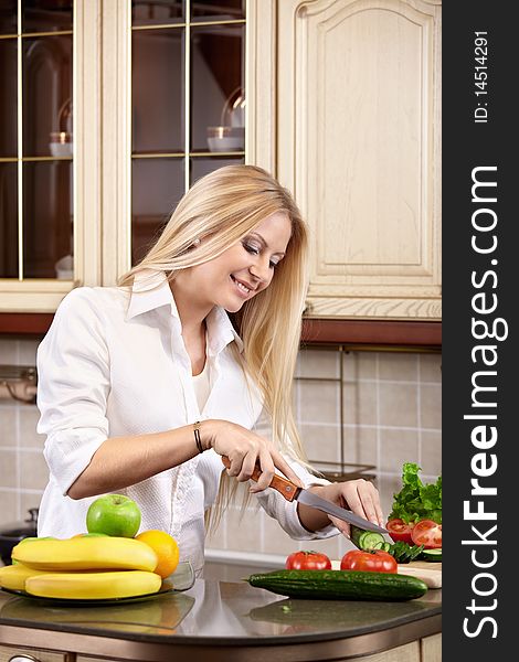 The attractive girl cuts vegetables on kitchen. The attractive girl cuts vegetables on kitchen