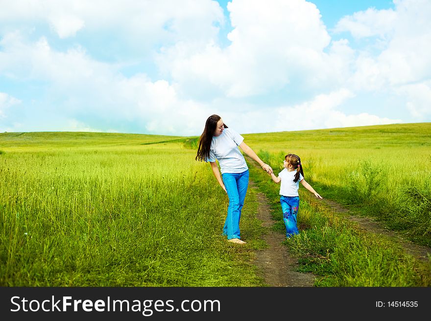 Young mother and her little daughter walking outdoors on a summer day. Young mother and her little daughter walking outdoors on a summer day