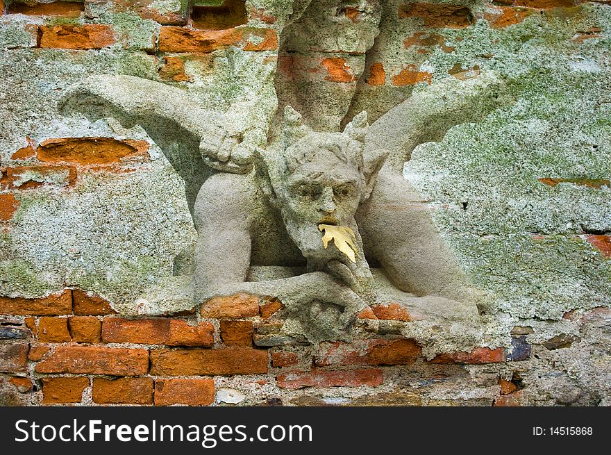Devil under foot of st. Michael. An old bricks wall with picture.