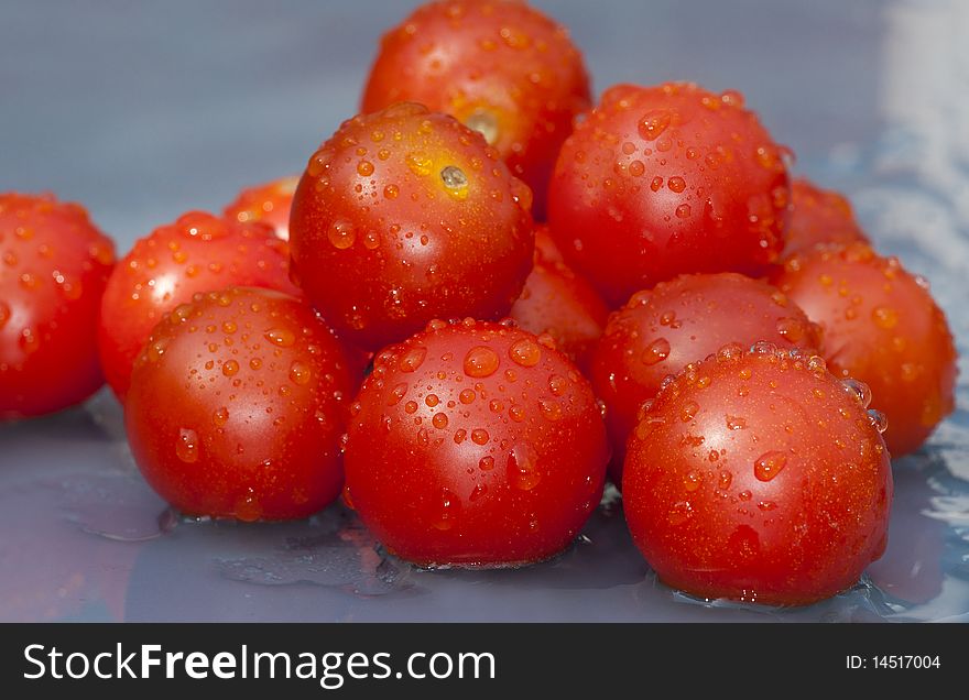 Bunch of cherry tomato on a blue wet background