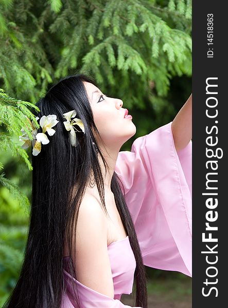 Beautiful asian woman in a pink dress with flowers in her hair. Beautiful asian woman in a pink dress with flowers in her hair