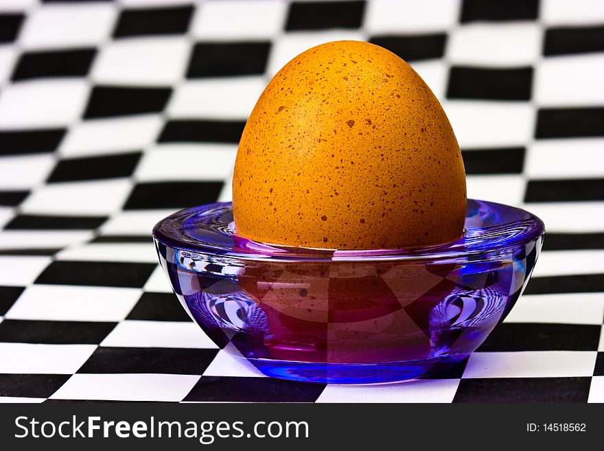 Egg on a transparent stand at the checkered background