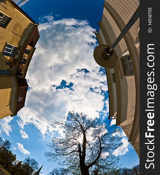 Shot with a fisheye lens looking up to the sky of a city from below between two houses. Shot with a fisheye lens looking up to the sky of a city from below between two houses