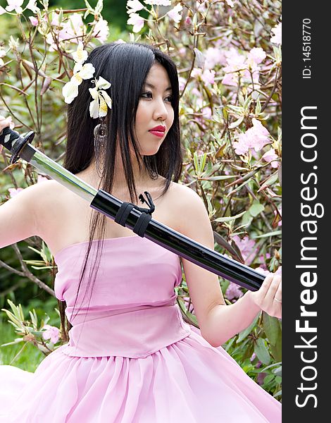 Beutiful japanese woman in pink dress wields a sword