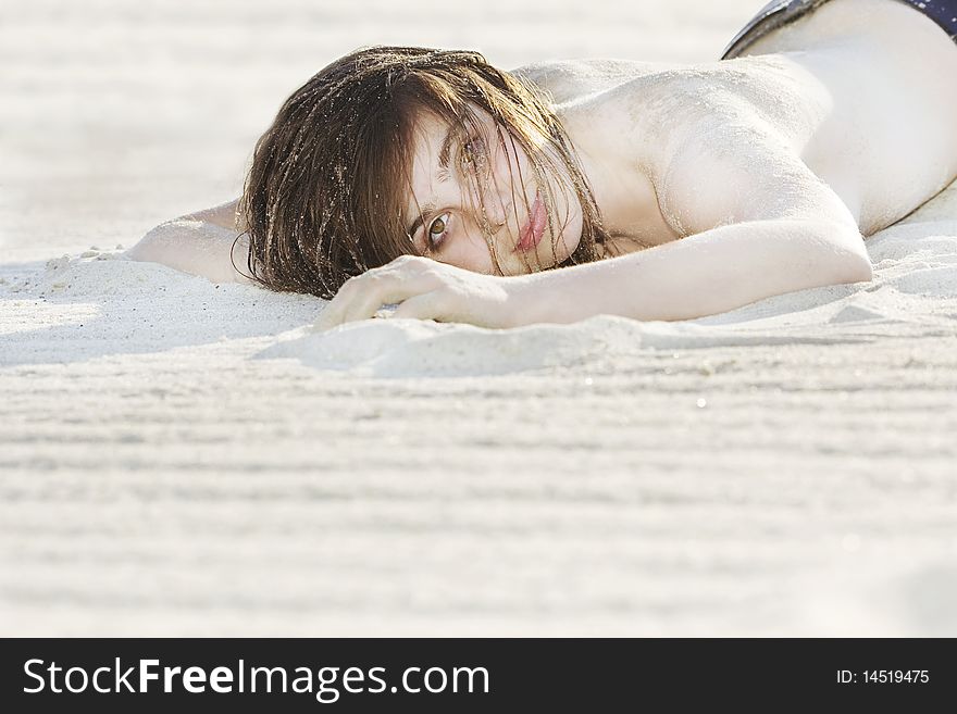 Portrait of beautiful fashion model laying on the sand. Portrait of beautiful fashion model laying on the sand