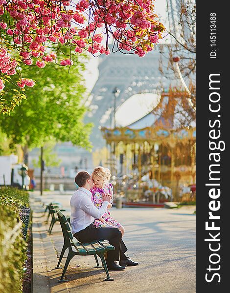 Couple under blooming cherry tree on a spring day with Eiffel tower