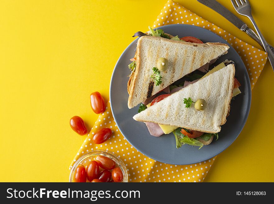 Sandwich with ham. Toasted double panini with ham, cheese fresh vegetables.Yellow background. Copy space food lettuce turkey olive bread meat lunch snack meal breakfast dinner green tomato grilled delicious rustic wooden club cuisine slice tasty gourmet healthy salad melt hot pressed cut smoked crispy heated white work triangle cherry take away colorful summer
