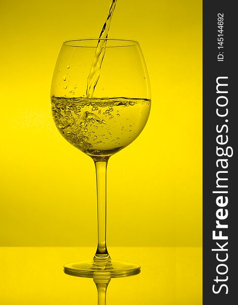 Full wine glass on yellow background, full wineglass on green light
