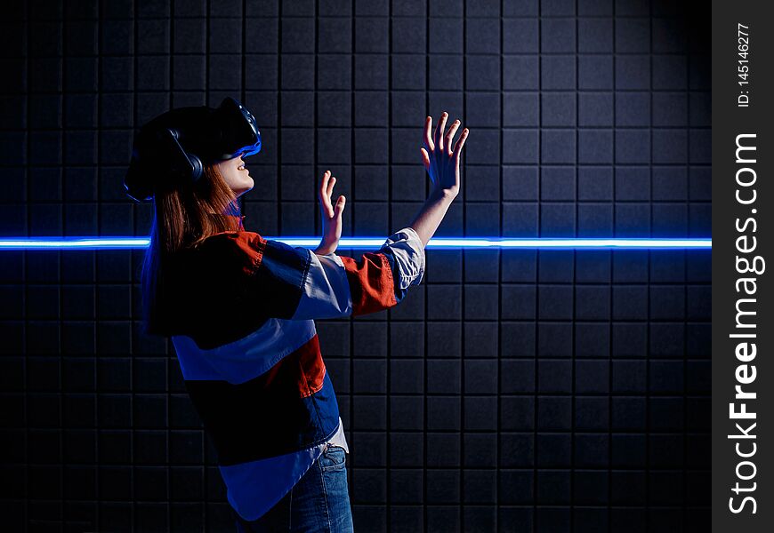 Young girl in a virtual reality helmet in a video game club. Woman surprised in glasses of virtual reality. Young girl in a virtual reality helmet in a video game club. Woman surprised in glasses of virtual reality