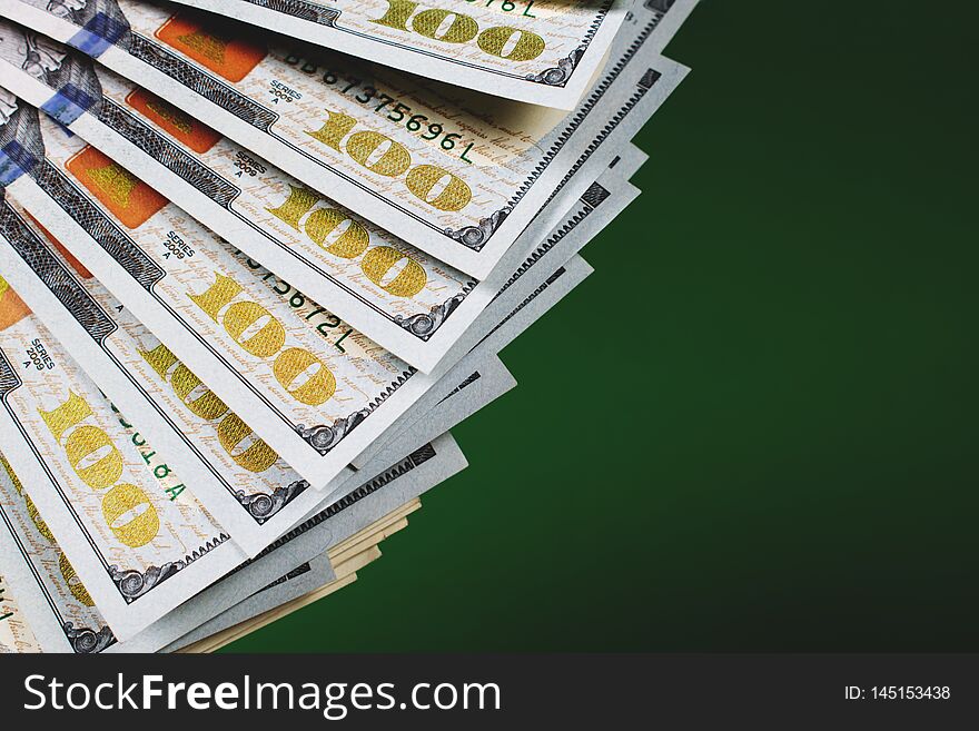 Fan of one hundred dollar banknotes on a green background with copy space for text. Budgeting, finance and saving concept. Fan of one hundred dollar banknotes on a green background with copy space for text. Budgeting, finance and saving concept