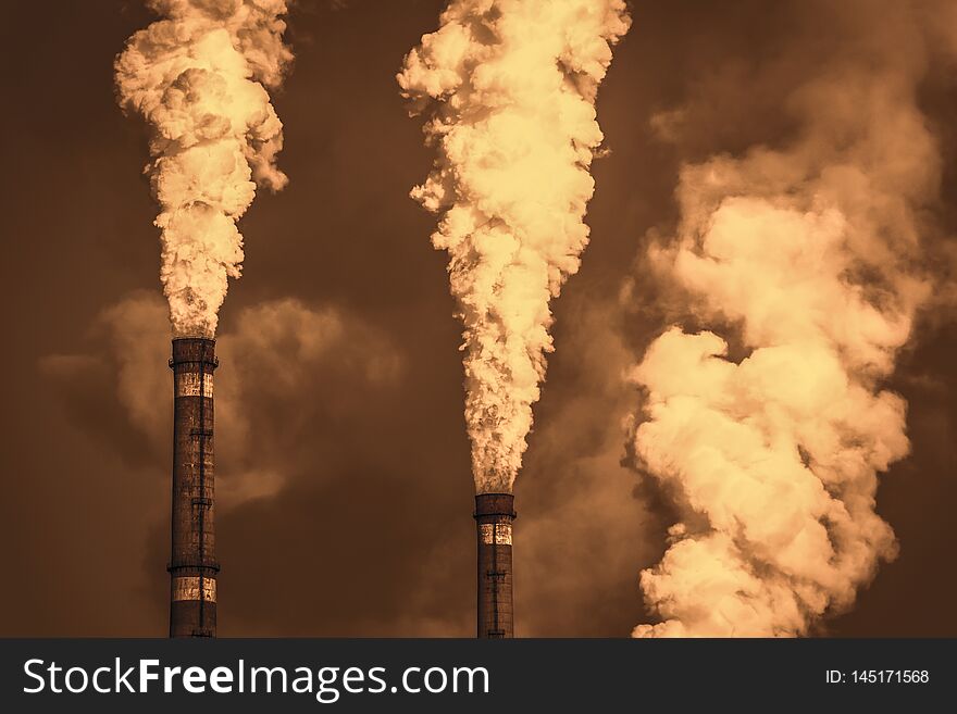 The thick smoke rises high from the industrial pipes. Pollution of the environment with waste products. The thick smoke rises high from the industrial pipes. Pollution of the environment with waste products