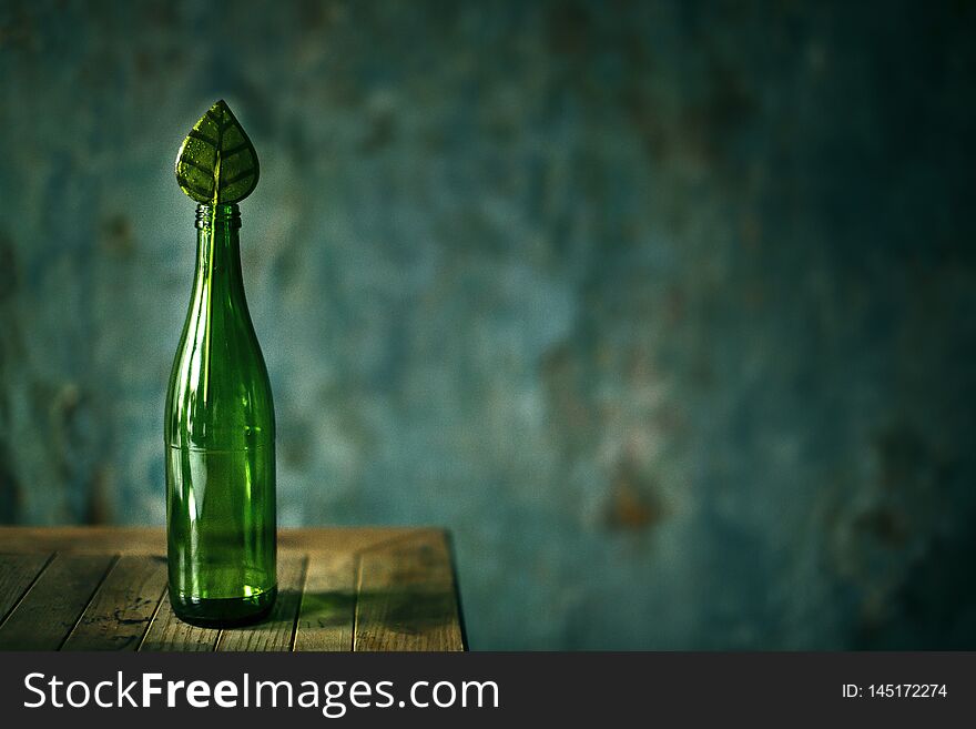 Glass green empty bottle on dark background with candy
