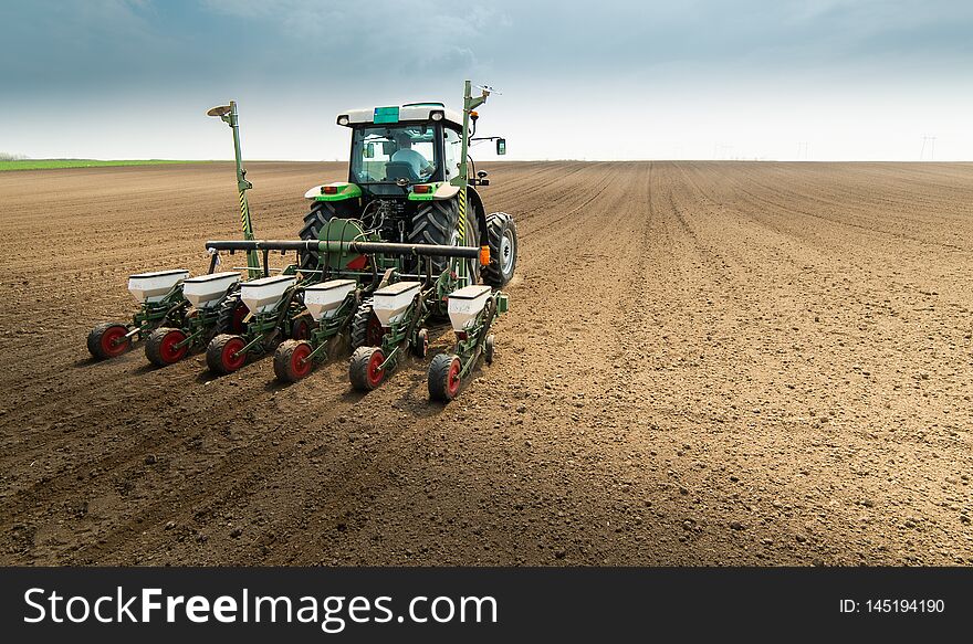 Farmer with tractor seeding sowing crops at agricultural field