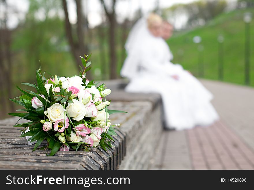 Wedding bouquet in the foreground, the background newlyweds