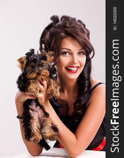 Young beautiful brunette woman in a black dress with a Yorkshire terrier. Young beautiful brunette woman in a black dress with a Yorkshire terrier