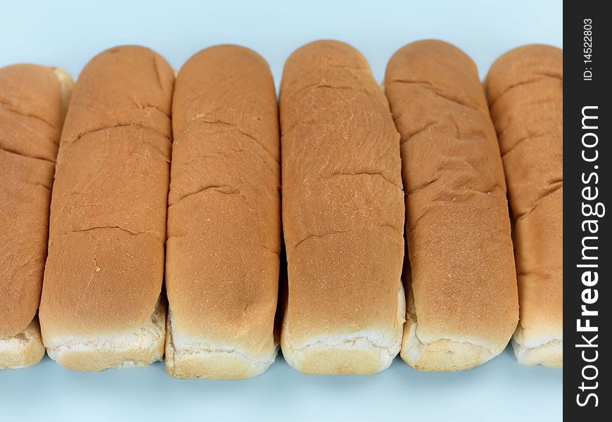 Plain hotdog buns isolated against a blue background