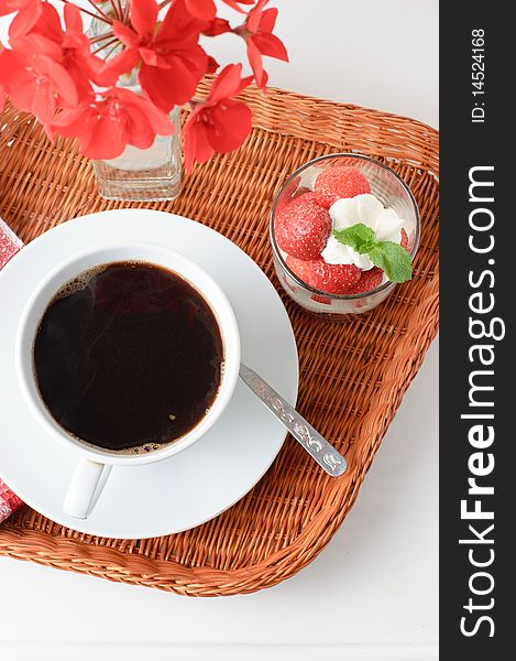 Wicker tray with breakfast of coffee and strawberry dessert