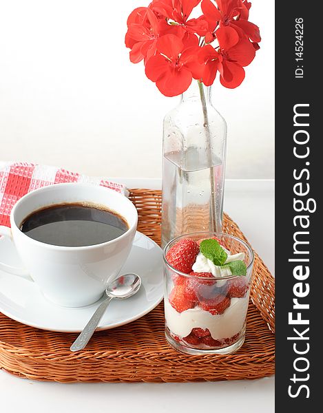 Wicker tray with breakfast of coffee and strawberry dessert