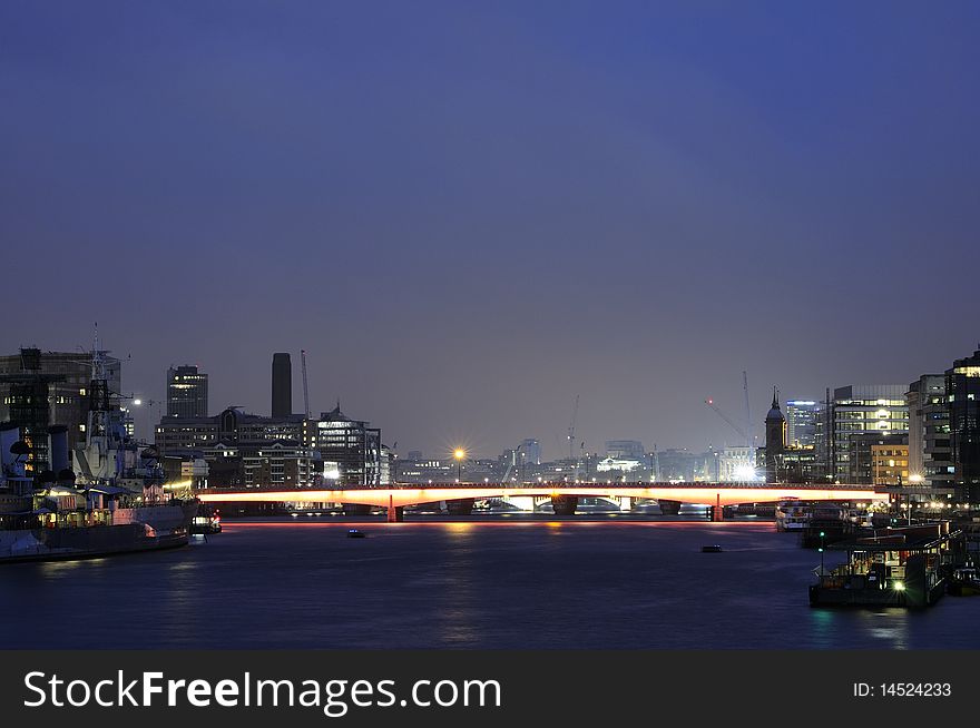 Thames river and London Bridge with illuminated modern buildings in background. Thames river and London Bridge with illuminated modern buildings in background