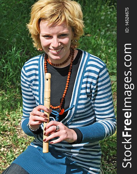 Young blond woman with wooden reed outdoor. Young blond woman with wooden reed outdoor