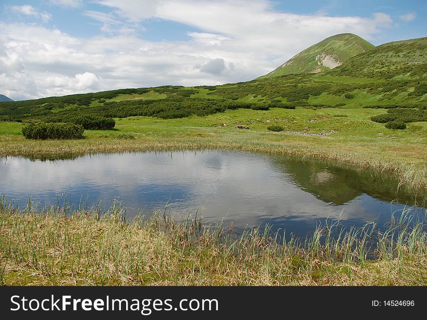 Mountain top an summer landscape with hillside under clouds