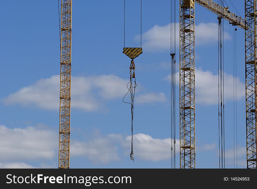 Elevating construction crane against the blue sky in a fair weather