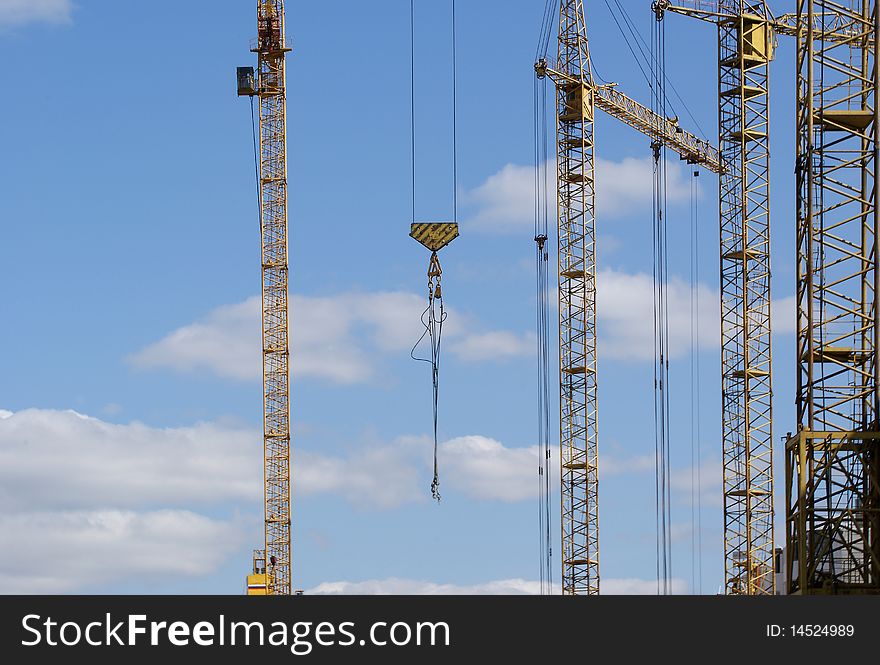 Elevating construction crane against the blue sky in a fair weather